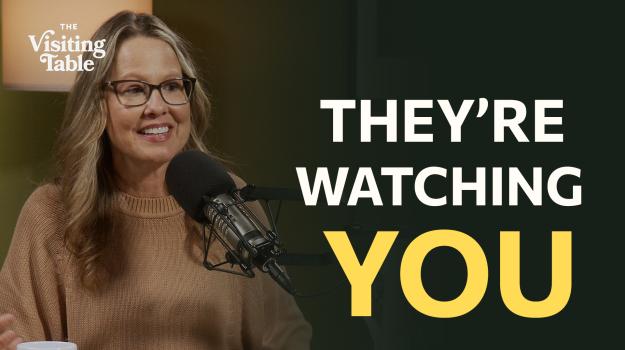 Julie Norton in The Visiting Table studio beside the words “They’re Watching You.”
